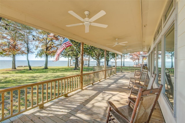 wooden deck with a yard, ceiling fan, a water view, and covered porch