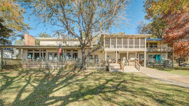 back of house with a chimney, a sunroom, a lawn, and a deck