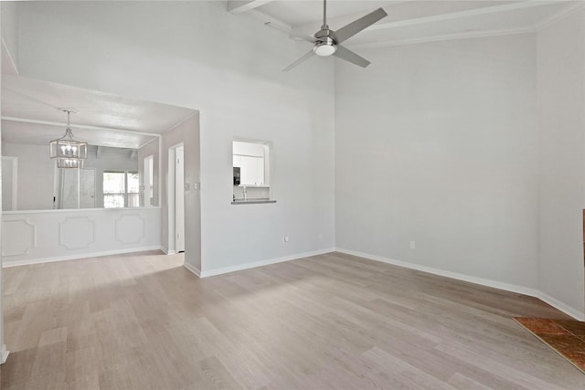 empty room featuring crown molding, ceiling fan with notable chandelier, and light hardwood / wood-style floors