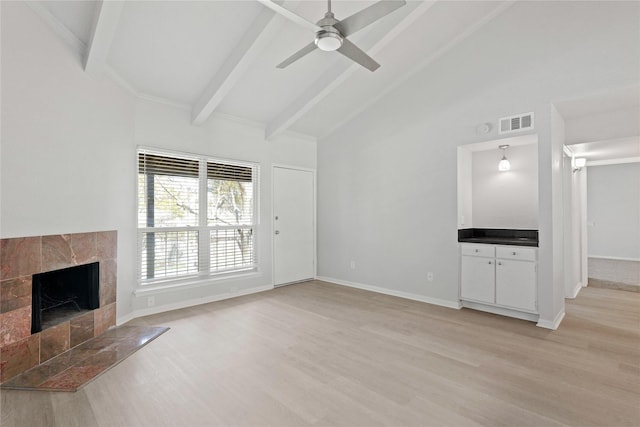 unfurnished living room featuring beam ceiling, high vaulted ceiling, a fireplace, and light hardwood / wood-style floors