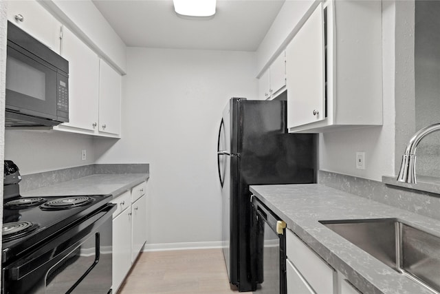 kitchen with sink, black appliances, light hardwood / wood-style floors, and white cabinets