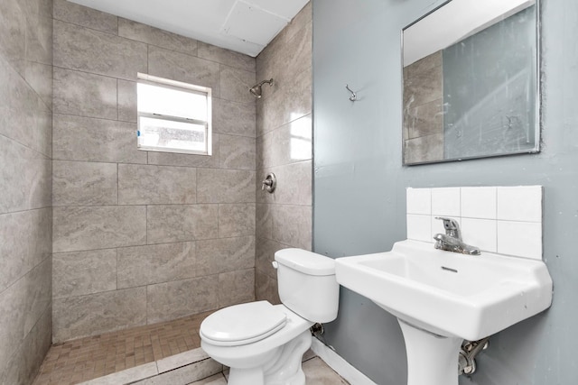 bathroom with tiled shower, sink, and toilet