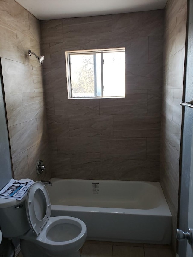 bathroom featuring toilet, tiled shower / bath combo, and tile patterned flooring