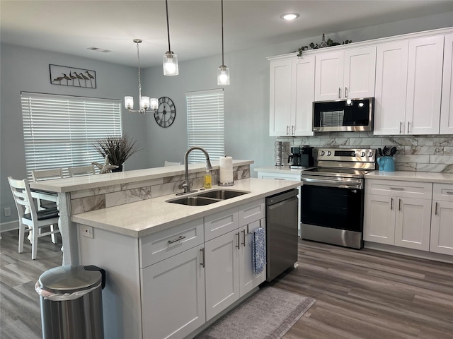 kitchen with stainless steel appliances, white cabinetry, sink, and pendant lighting