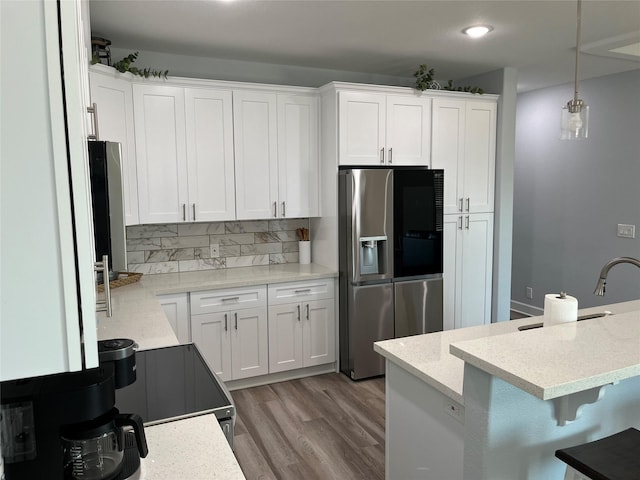 kitchen featuring pendant lighting, stainless steel fridge, light hardwood / wood-style floors, and white cabinets