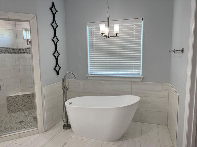 bathroom with shower with separate bathtub, tile walls, and a chandelier