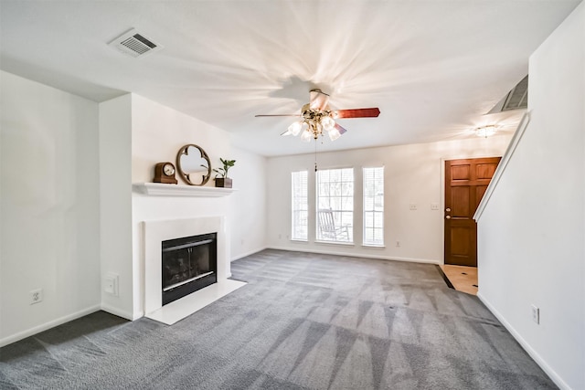 unfurnished living room with carpet floors, a fireplace with flush hearth, visible vents, and a ceiling fan