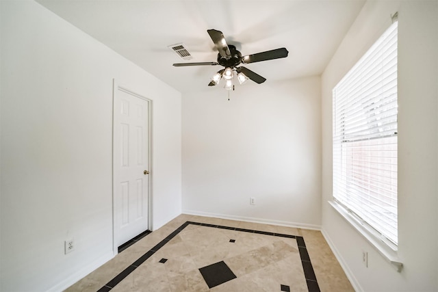 spare room featuring a ceiling fan, visible vents, and baseboards