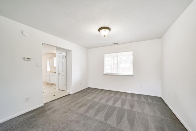 empty room featuring carpet, visible vents, and baseboards