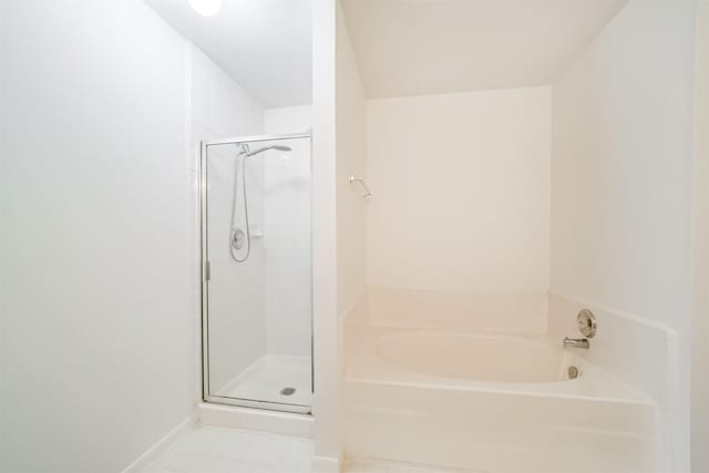 full bathroom featuring a stall shower, a garden tub, and baseboards