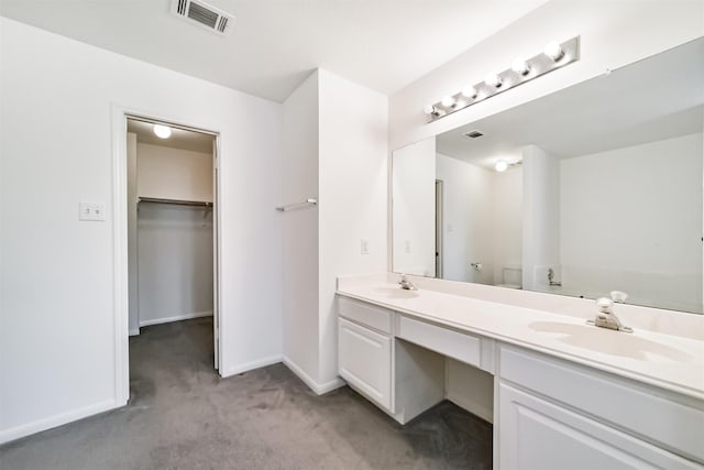 bathroom with double vanity, a sink, visible vents, and a walk in closet