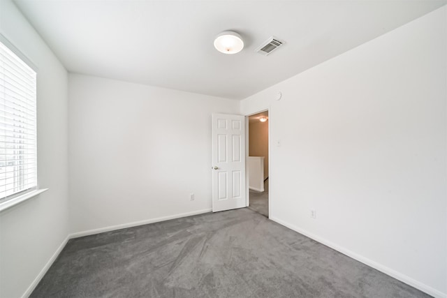 spare room featuring carpet floors, visible vents, and baseboards