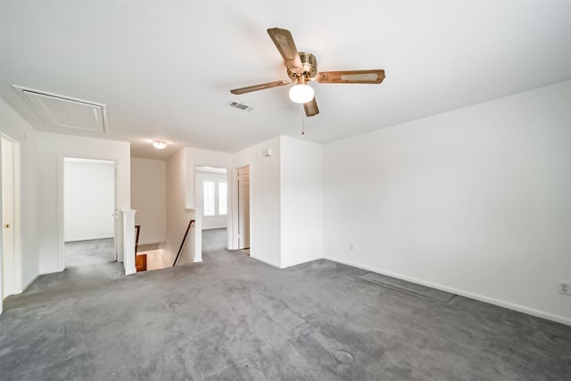 carpeted spare room featuring baseboards, attic access, visible vents, and a ceiling fan