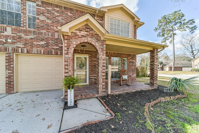 view of exterior entry featuring a garage and brick siding