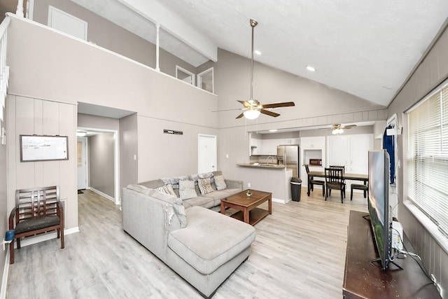 living room with sink, high vaulted ceiling, ceiling fan, and light wood-type flooring