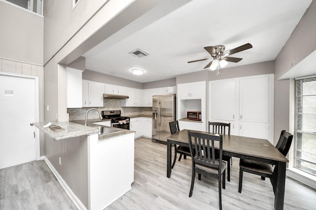 kitchen with white cabinetry, light wood-type flooring, appliances with stainless steel finishes, kitchen peninsula, and backsplash