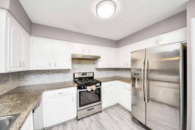 kitchen featuring stainless steel appliances, white cabinetry, decorative backsplash, and dark stone counters