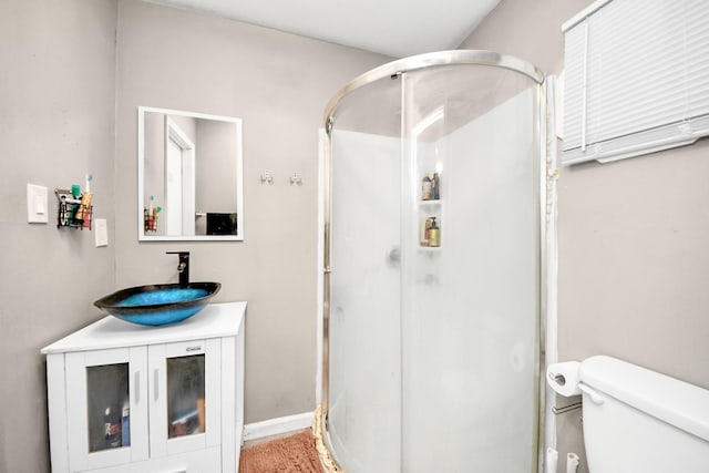 bathroom featuring vanity, a shower with door, and toilet