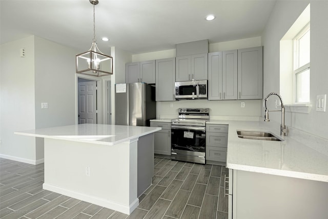 kitchen with pendant lighting, sink, gray cabinetry, stainless steel appliances, and a center island