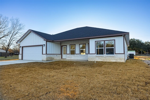 view of front of property featuring cooling unit, a garage, and a front lawn