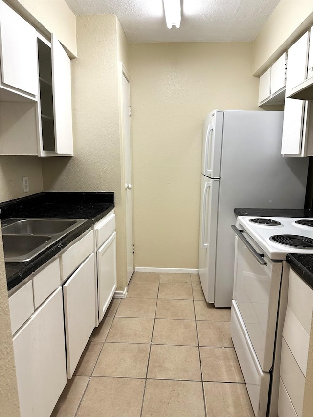 kitchen with light tile patterned floors, electric range, sink, and white cabinets