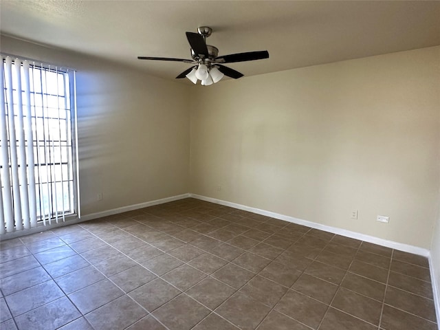 unfurnished room featuring dark tile patterned floors and ceiling fan