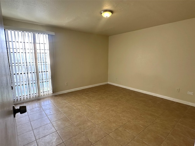 unfurnished room featuring tile patterned flooring and a textured ceiling