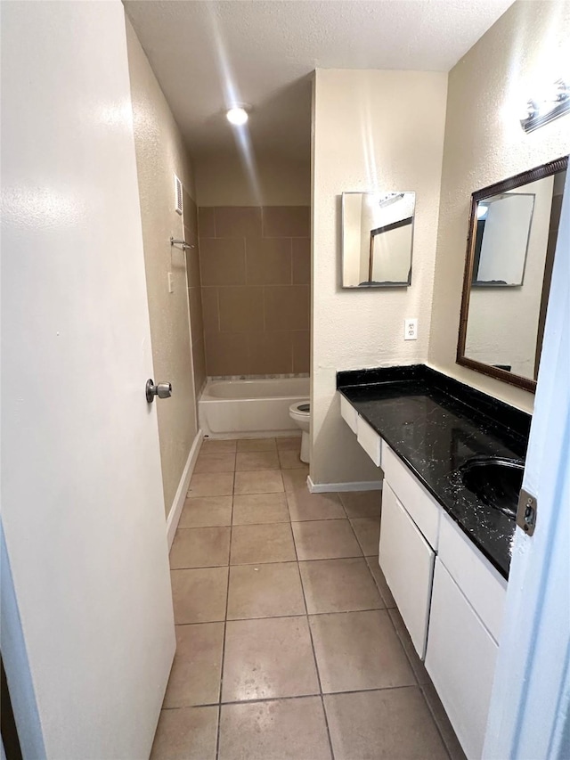 full bathroom featuring tiled shower / bath combo, vanity, a textured ceiling, tile patterned floors, and toilet