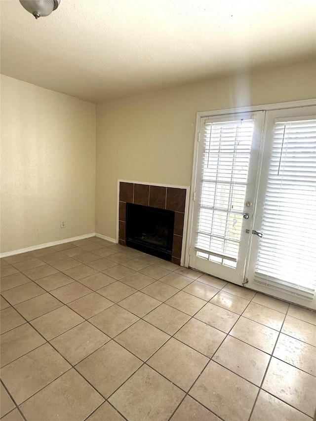 unfurnished living room featuring a tiled fireplace, light tile patterned floors, and a textured ceiling