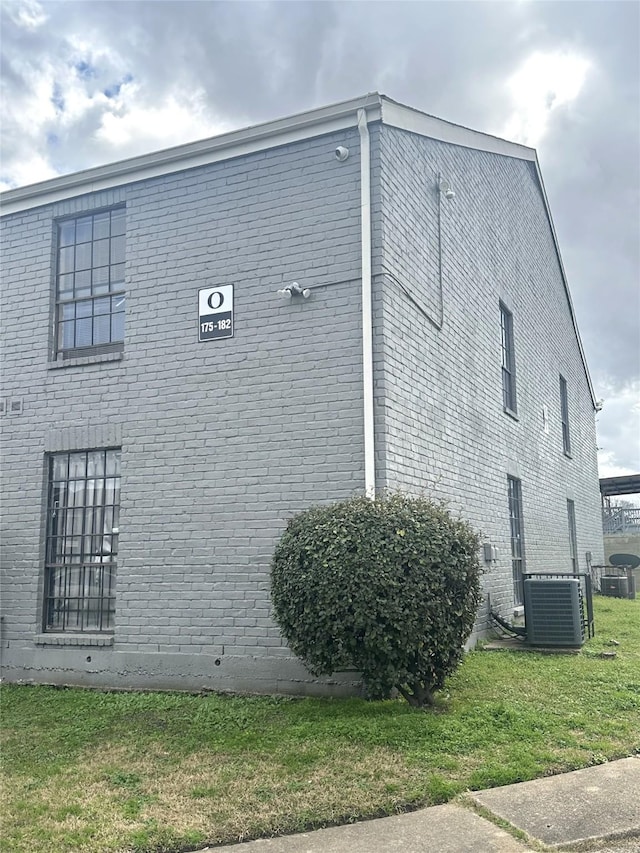 view of side of property with cooling unit and a lawn