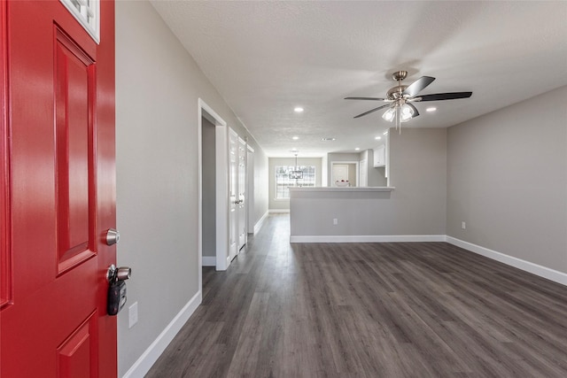 interior space featuring dark wood-type flooring, ceiling fan with notable chandelier, and a textured ceiling