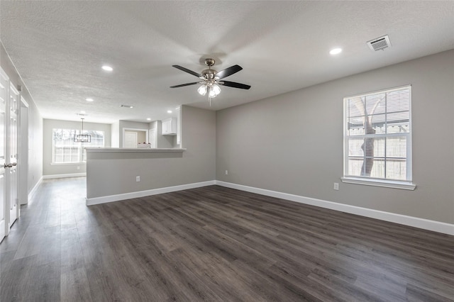 unfurnished living room with dark hardwood / wood-style floors, ceiling fan with notable chandelier, and a textured ceiling