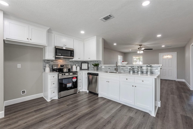 kitchen with stainless steel appliances, sink, white cabinets, and kitchen peninsula