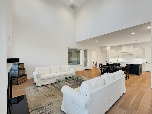 living room with a towering ceiling and light hardwood / wood-style flooring