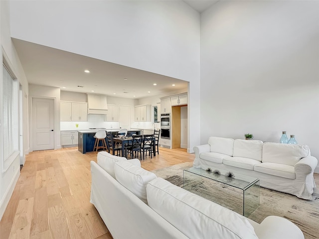 living room featuring a towering ceiling and light hardwood / wood-style floors