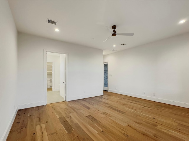 unfurnished bedroom featuring ceiling fan, ensuite bath, and light wood-type flooring