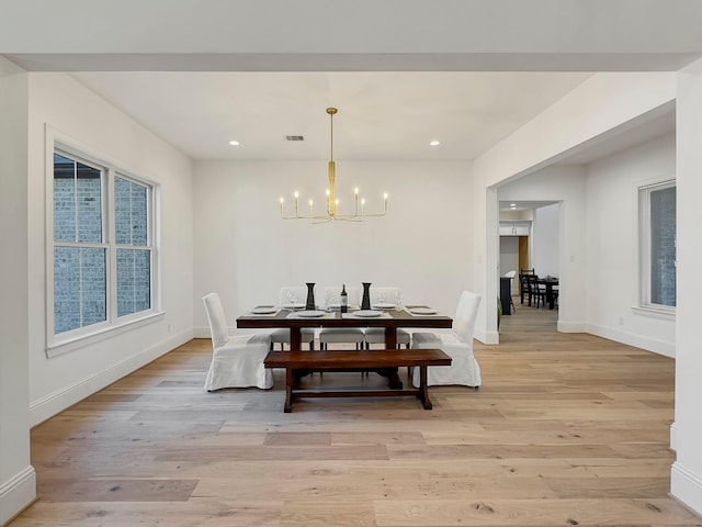 dining space with an inviting chandelier and light hardwood / wood-style flooring