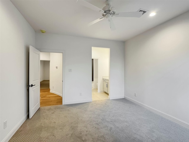 unfurnished bedroom with ceiling fan, light colored carpet, and ensuite bath