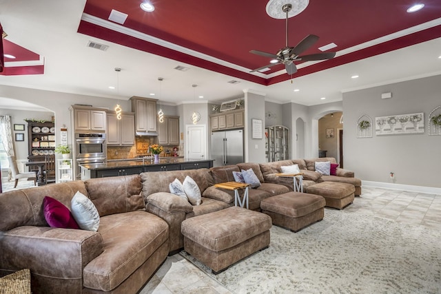 living room featuring ceiling fan, ornamental molding, and a tray ceiling