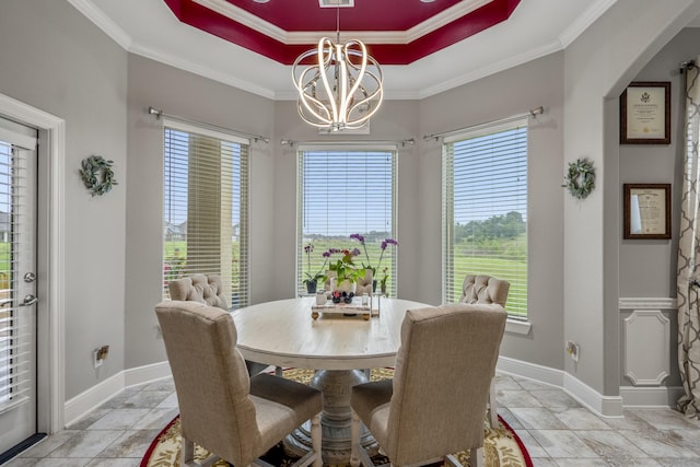 dining space with an inviting chandelier, a tray ceiling, and crown molding