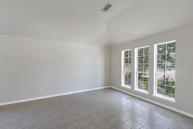 spare room featuring lofted ceiling and light tile patterned flooring