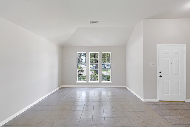 tiled spare room with vaulted ceiling