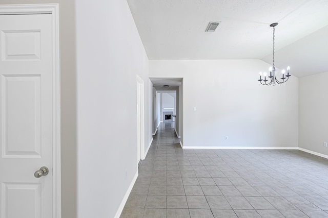 tiled spare room featuring lofted ceiling and a notable chandelier