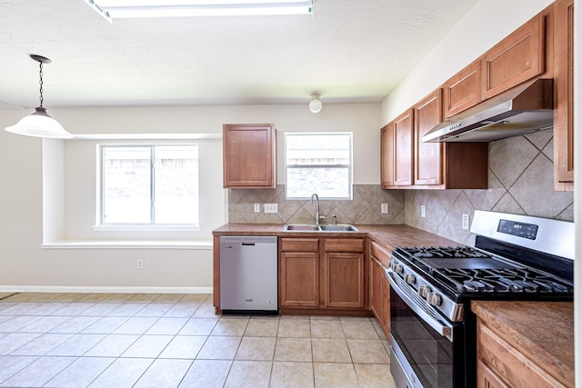 kitchen with appliances with stainless steel finishes, decorative light fixtures, sink, decorative backsplash, and light tile patterned floors