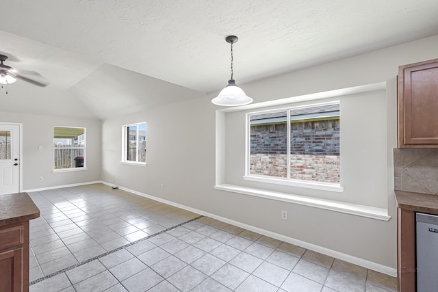 unfurnished dining area with lofted ceiling, light tile patterned floors, a textured ceiling, and ceiling fan