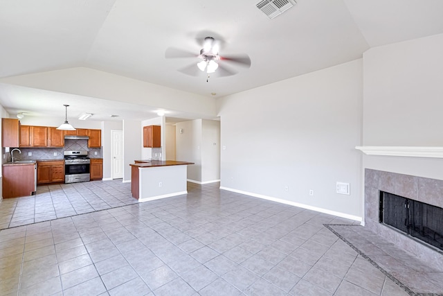 unfurnished living room featuring light tile patterned flooring, ceiling fan, lofted ceiling, and a tile fireplace