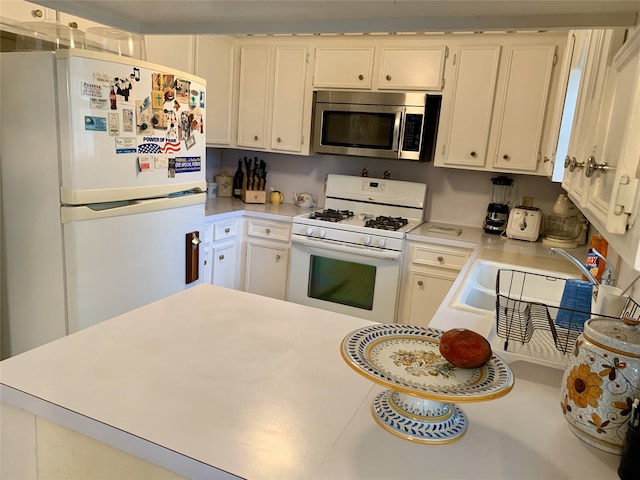 kitchen with white appliances, a sink, light countertops, and white cabinets