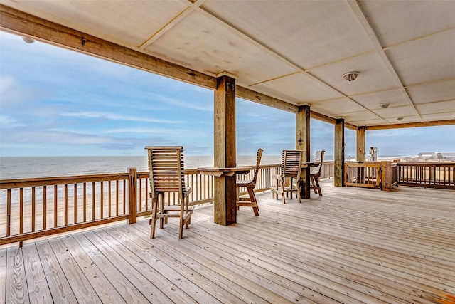 wooden deck featuring a water view and a view of the beach