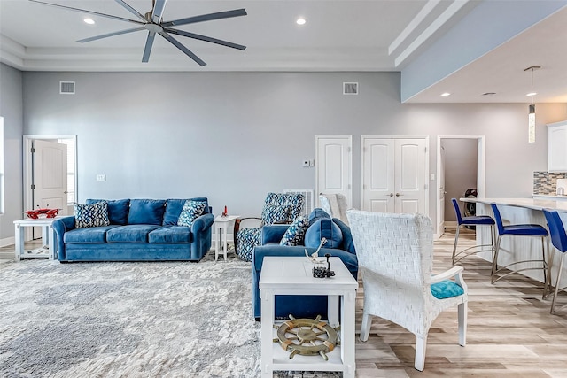 living room featuring a tray ceiling, a high ceiling, and light wood-type flooring