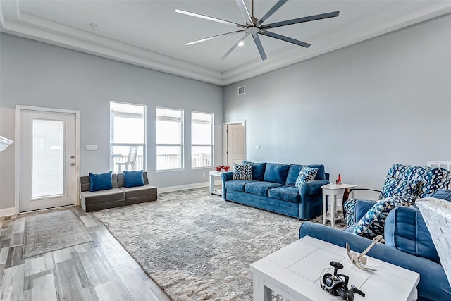 living room featuring ceiling fan, a towering ceiling, and wood-type flooring